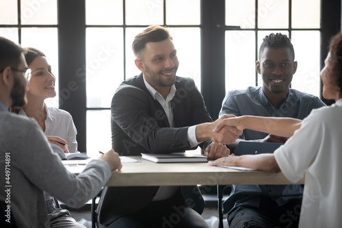 Smiling businessman shake hand of business partner get acquainted greet at meeting in office, happy multiracial diverse businesspeople handshake close deal or make agreement. Cooperation concept.