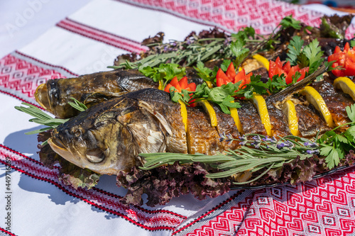 Delicious stuffed carp with lemon, tomato and herbs, close up