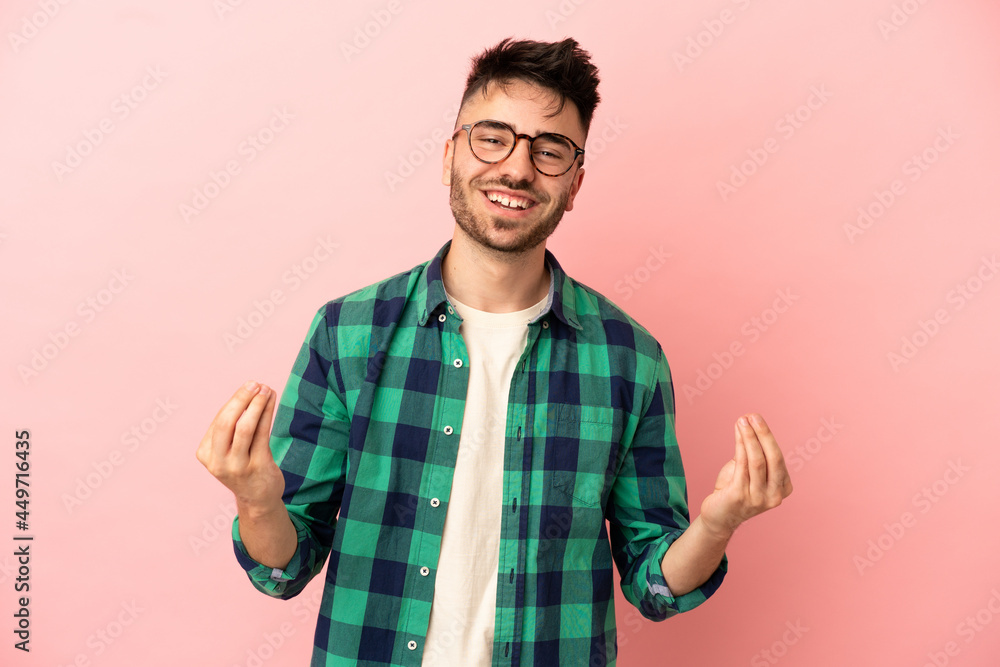 Young caucasian man isolated on pink background making money gesture Young caucasian man isolated on pink background making money gesture