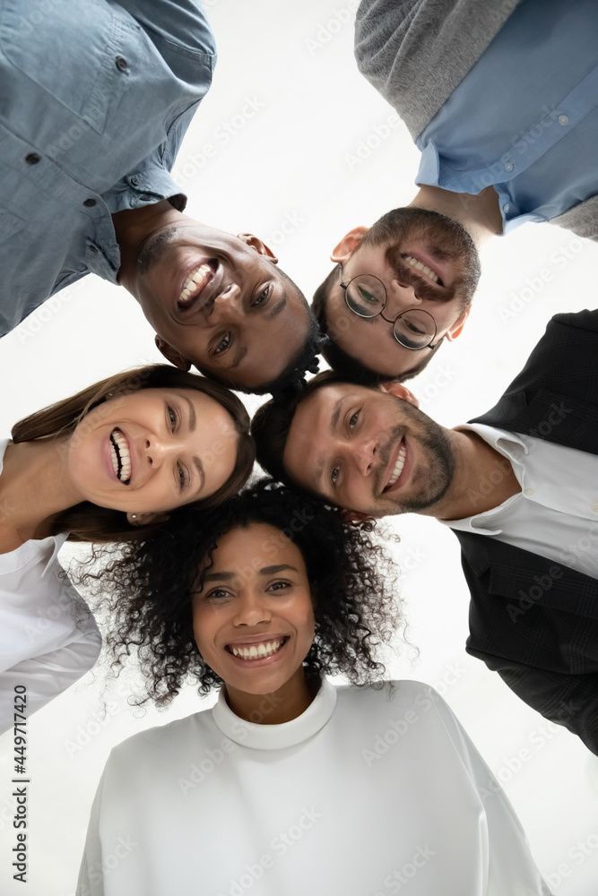 © fizkes - Close up vertical low angle portrait of smiling multiethnic diverse employees pose together look at camera laughing. Happy young multiracial workers friends have fun show unity. Diversity concept. © fizkes - Close up vertical low angle portrait of smiling multiethnic diverse employees pose together look at camera laughing. Happy young multiracial workers friends have fun show unity. Diversity concept.