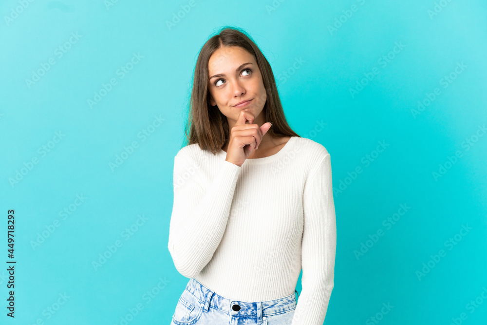Young woman over isolated blue background and looking up Young woman over isolated blue background and looking up