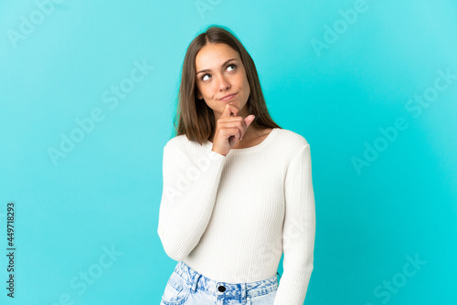 Young woman over isolated blue background and looking up