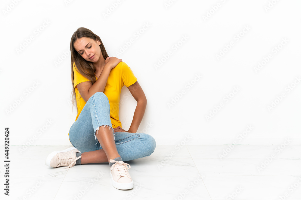 Young girl sitting on the floor suffering from pain in shoulder for having made an effort Young girl sitting on the floor suffering from pain in shoulder for having made an effort