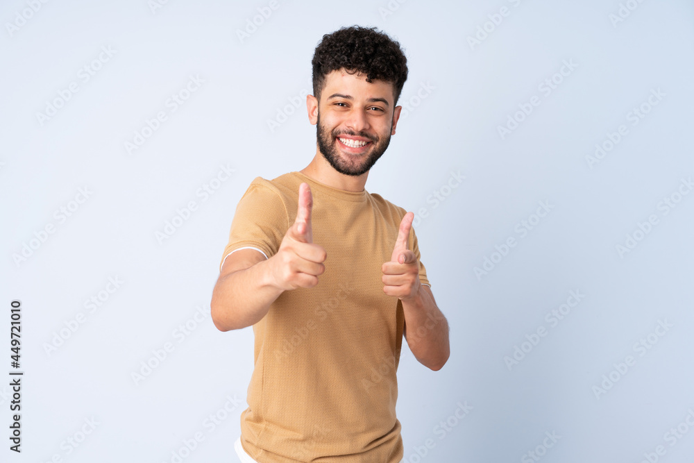 Young Moroccan man isolated on blue background pointing to the front and smiling Young Moroccan man isolated on blue background pointing to the front and smiling