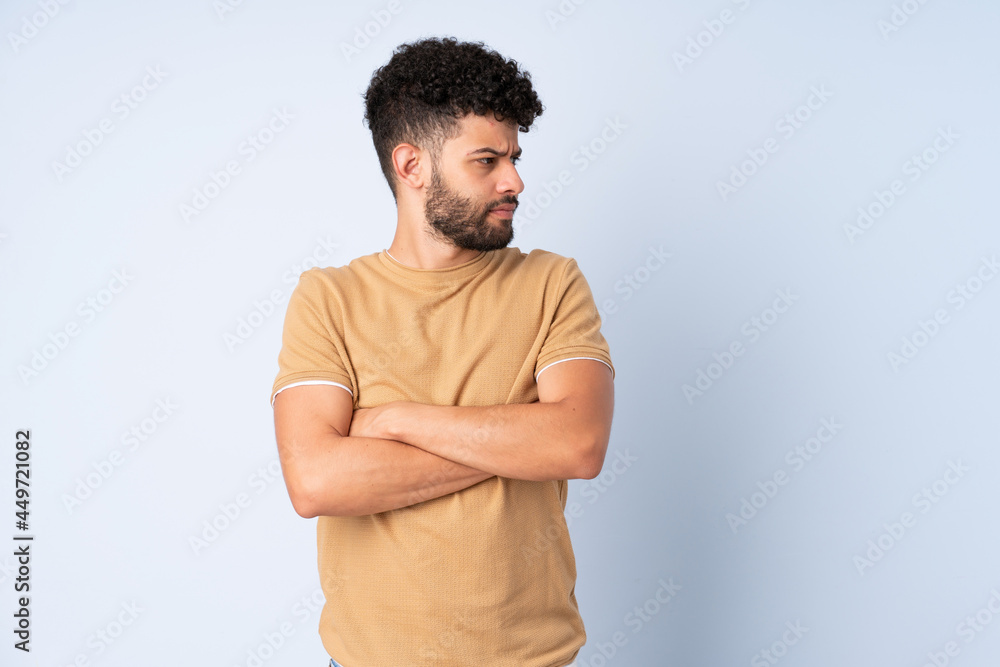Fototapeta premium Young Moroccan man isolated on blue background keeping the arms crossed
