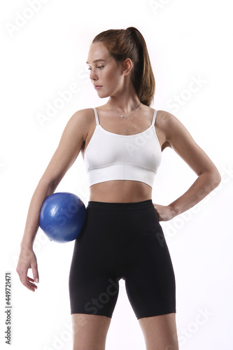 Beautiful young sportswoman with fitness ball over white background