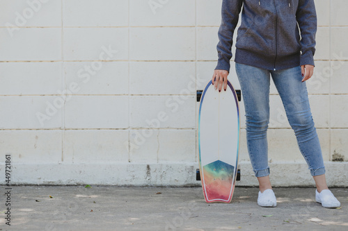 Cropped shot of woman in casual outfit with surfskate against concrete wall. active lifestyle concept photo