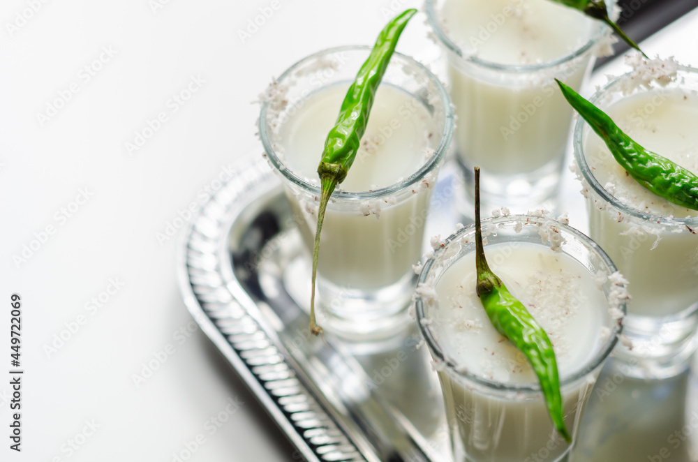 Coconut cocktail in drink shot glass decorated with coconut flakes and green bird eye chilli served on a silver tray Coconut cocktail in drink shot glass decorated with coconut flakes and green bird eye chilli served on a silver tray