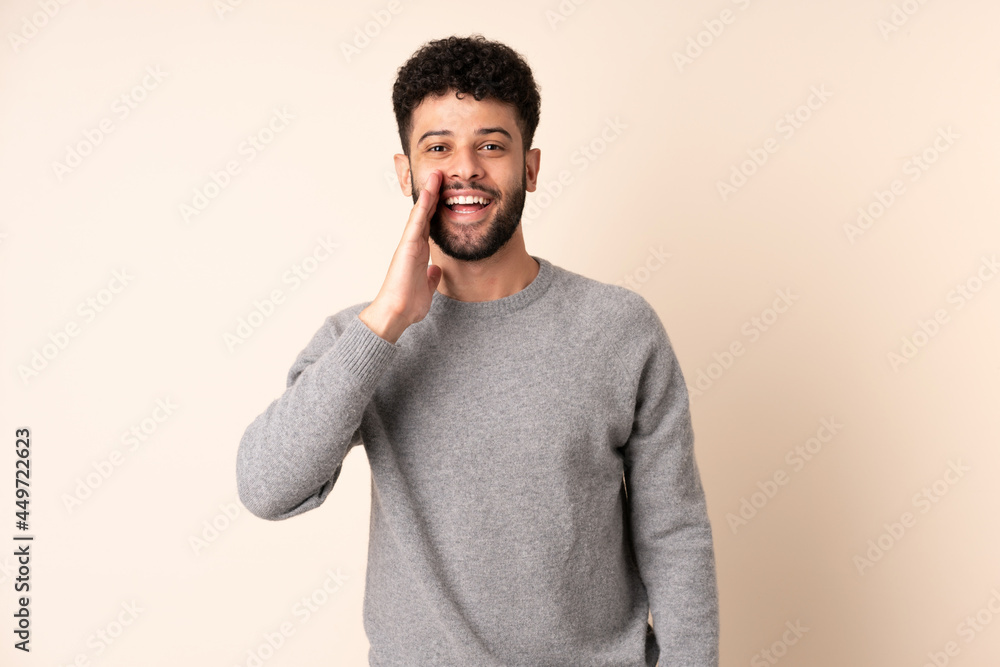 Young Moroccan man isolated on beige background shouting with mouth wide open Young Moroccan man isolated on beige background shouting with mouth wide open