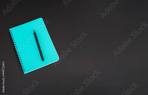 Top view of closed notebook with stationery on black school board.