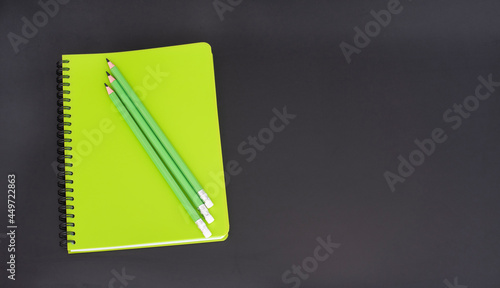 Top view of closed notebook with stationery on black school board.