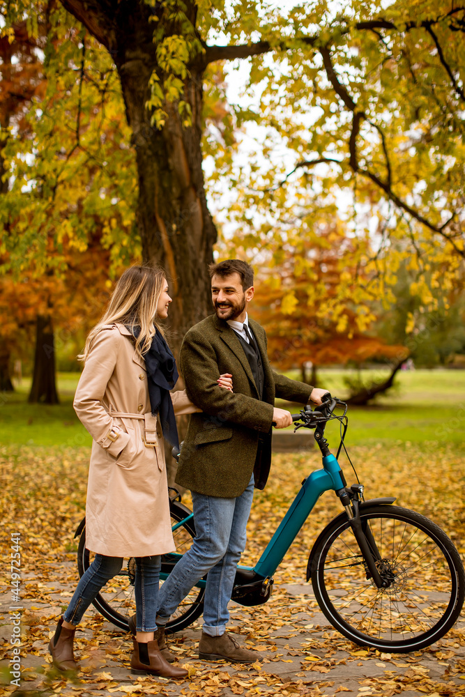 Young couple in the autumn park with electrical bicycle Young couple in the autumn park with electrical bicycle