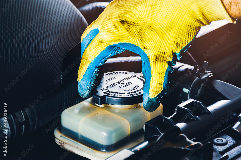 © BLKstudio - The mechanic hand is open or close the cap of the power steering fluid to check the hydraulic fluid level © BLKstudio - The mechanic hand is open or close the cap of the power steering fluid to check the hydraulic fluid level