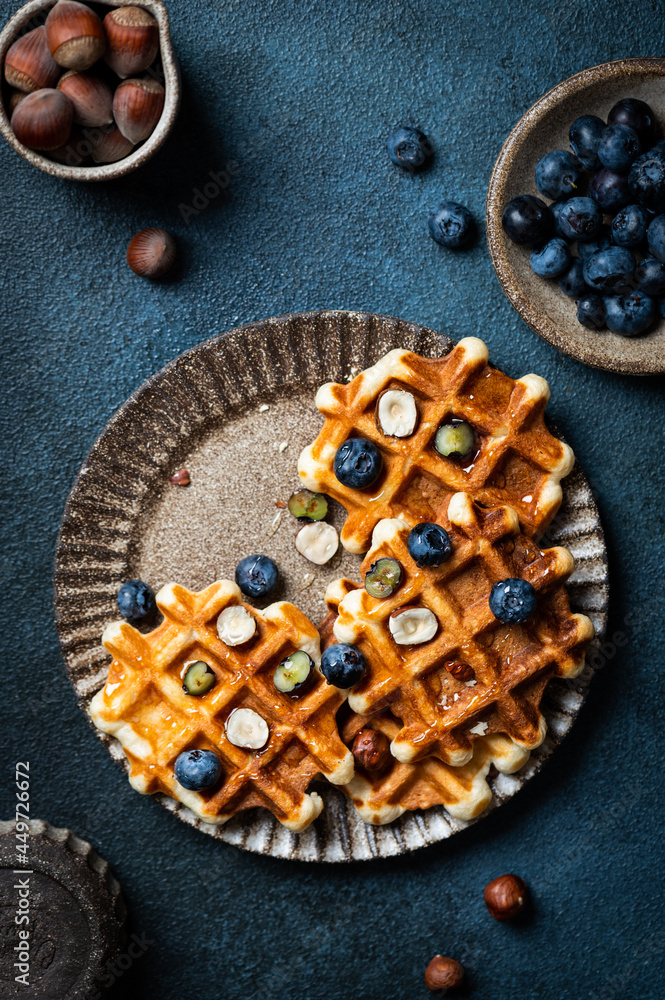 Freshly made belgian waffles with blueberry and hazelnut. Waffles with honey and berry. Place for text. Copy space. Classic sweet breakfast