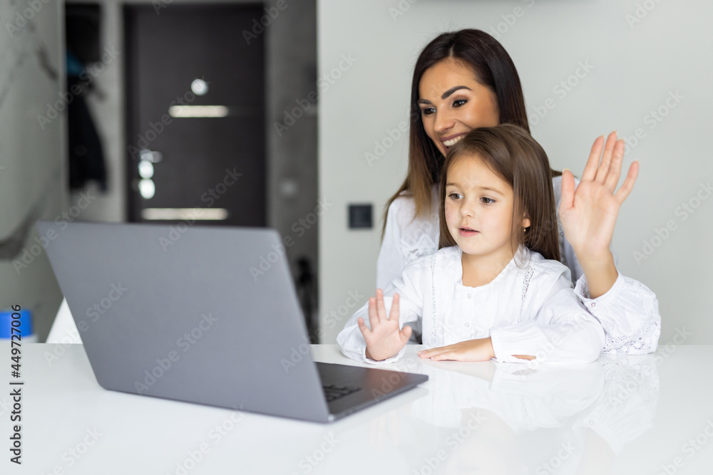 Mother and her daughter using video call on laptop at table in kitchen Mother and her daughter using video call on laptop at table in kitchen