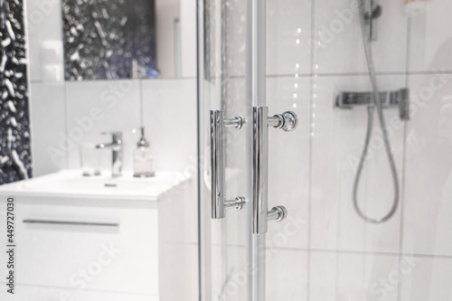 Close-up of chrome handles in a glass shower door. Modern bathroom interior