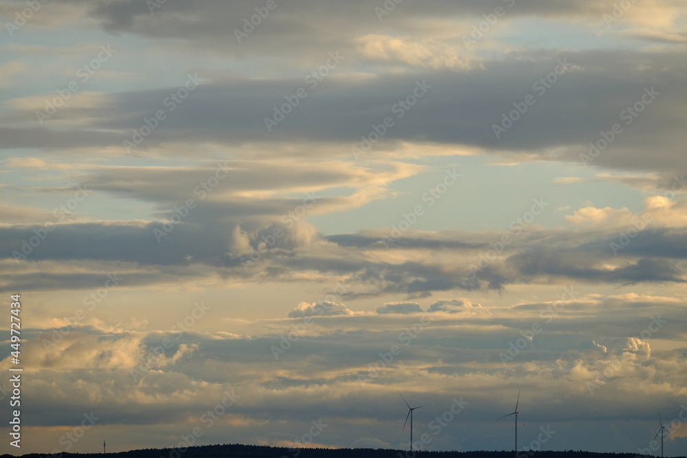 Sonnenuntergang mit sanften Pastellfarben geschichteten Wolken und Horizont mit Windrädern Querformat 