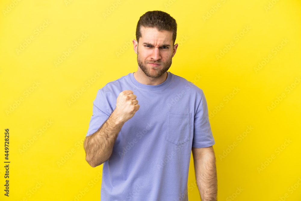 Handsome blonde man over isolated yellow background with unhappy expression Handsome blonde man over isolated yellow background with unhappy expression
