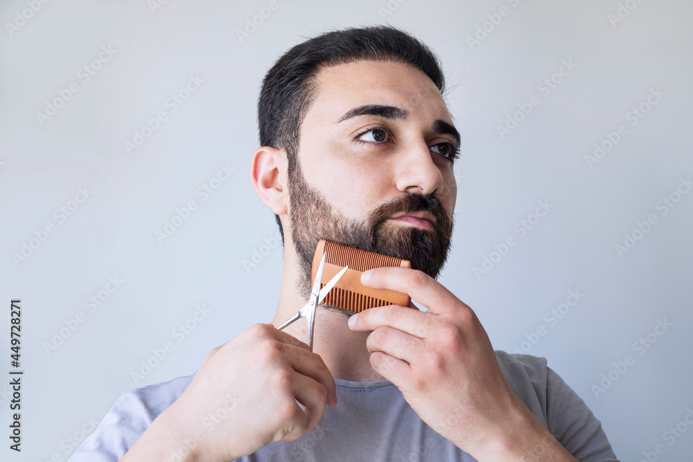 Portrait of a man cutting his beard with scissors. Selfcare during quarantine isolation Portrait of a man cutting his beard with scissors. Selfcare during quarantine isolation