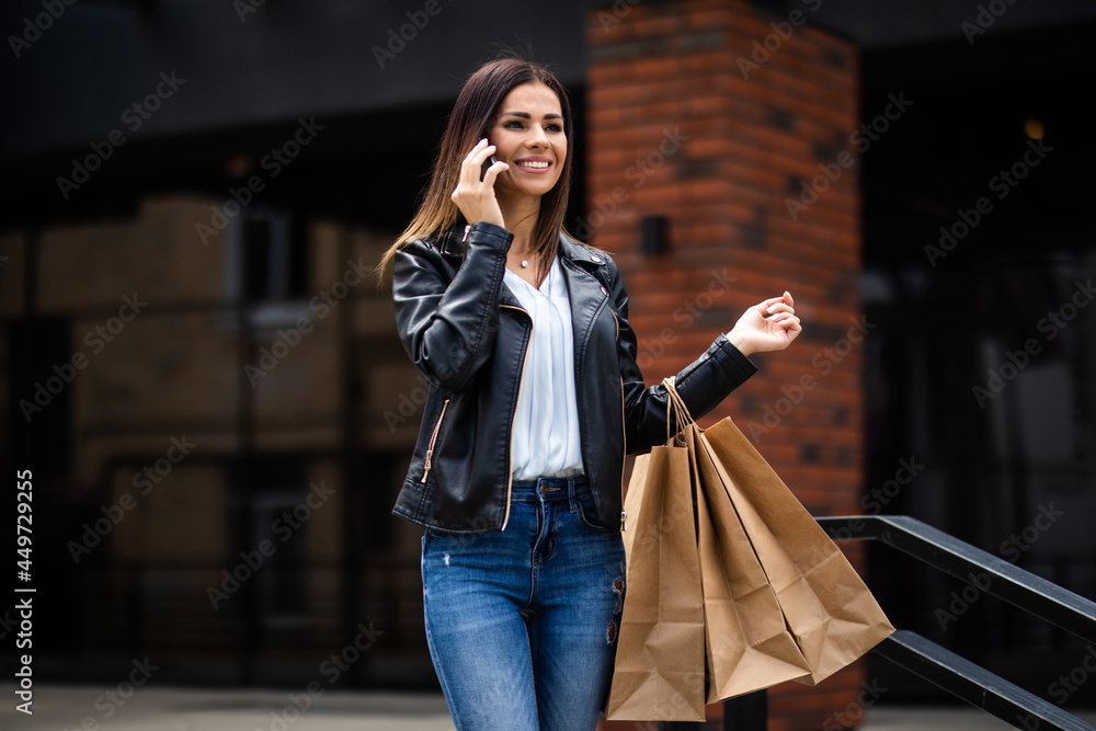 Young pretty woman talking on mobile phone out of shopping center.
