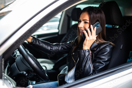 Young woman driving car and talking on mobile phone.