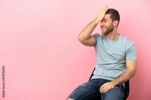 Young man sitting on a chair over isolated pink background has realized something and intending the solution © luismolinero