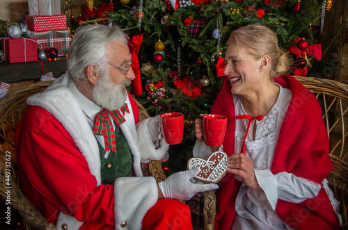 Santa Claus and wife Mrs. Claus near fireplace photo