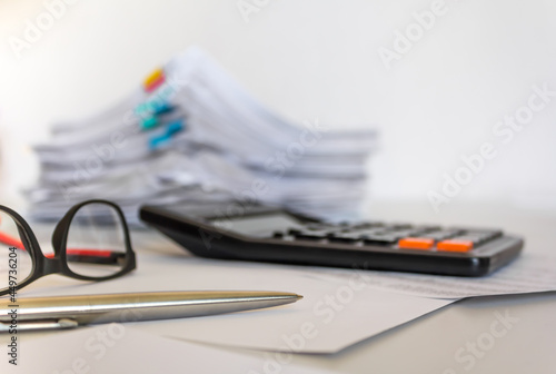 Stack of documents , calculator, pen placed on a business desk in a business office. Copy space