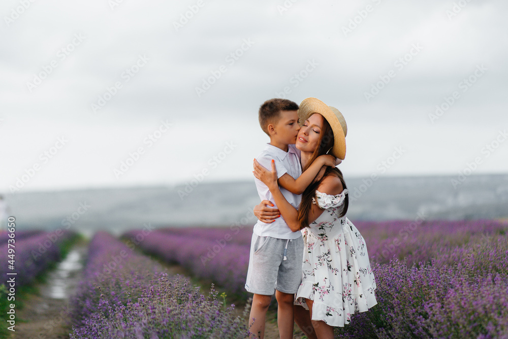 A young beautiful woman with her young son is walking through a beautiful field of lavender and enjoying the fragrance of flowers. Rest and beautiful nature. Unity with nature and harmony. A young beautiful woman with her young son is walking through a beautiful field of lavender and enjoying the fragrance of flowers. Rest and beautiful nature. Unity with nature and harmony.