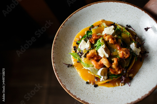salad with shrimps and brie cheese in a white plate on a dark background
