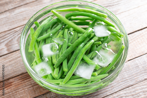 Boiled vegetables, green beans in ice water after blanching on a table