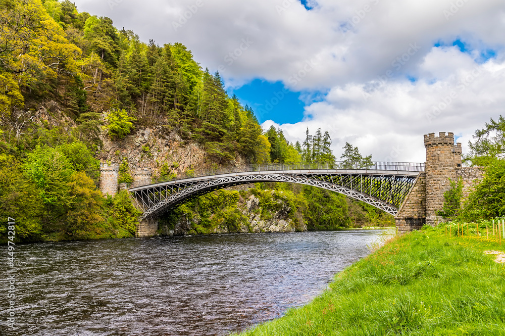 Fototapeta premium A view up the River Spey towards the castellated tower bridge at Craigellachie, Scotland on a summers day