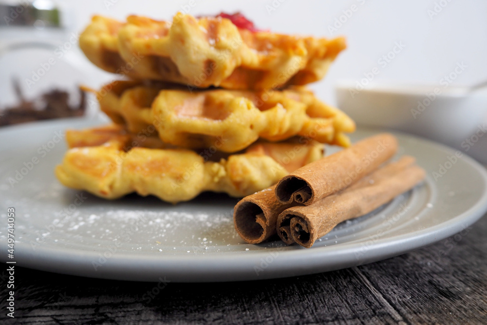 close gluten-free pumpkin Belgian waffles lie with cinnamon sticks on a gray plate on a white background side view close gluten-free pumpkin Belgian waffles lie with cinnamon sticks on a gray plate on a white background side view