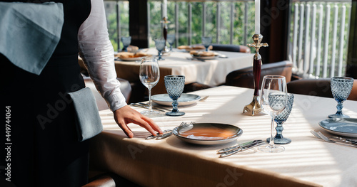 Photography A young waiter in a stylish uniform is engaged in serving the table in a beautiful gourmet restaurant close-up