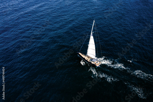 View from above, stunning aerial view of a sailboat sailing on a blue water at sunset. Costa Smeralda, Sardinia, Italy. © Travel Wild