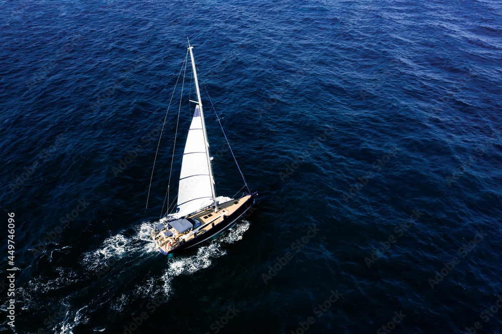 View from above, stunning aerial view of a sailboat sailing on a blue water at sunset.Sardinia, Italy.