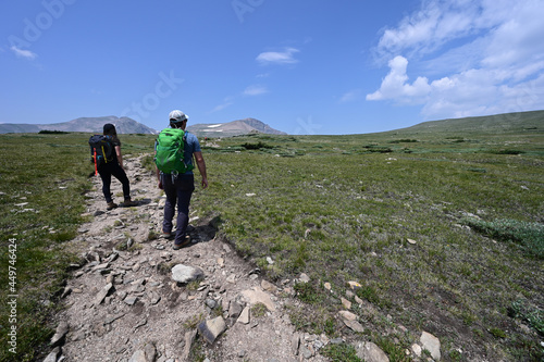 Hikers on trail in alpine tundra above St Mary's Glacier and above treeline in Arapaho National Forest, Colorado on sunny summer morning.