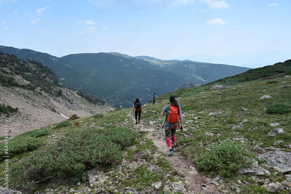 Hikers descend Saint Mary's Glacier Trail in Arapaho National Forest, Colorado on sunny summer afternoon.
