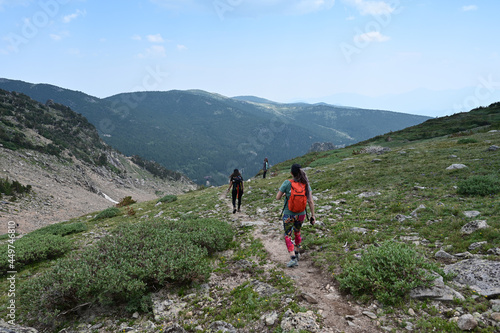 Hikers descend Saint Mary's Glacier Trail in Arapaho National Forest, Colorado on sunny summer afternoon.