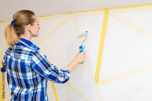 Young happy woman painting interior wall with paint roller in new house  Home decoration concept