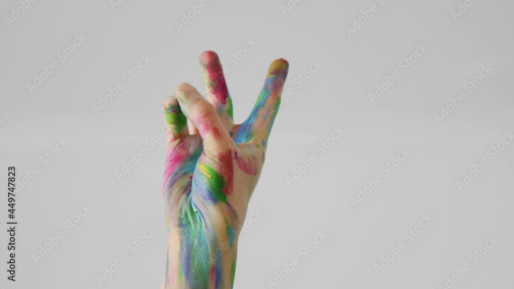 Hand of LGBT person painted with different colors shows victory or peace sign on white background, peaceful gesture of two fingers at the gay pride parade Hand of LGBT person painted with different colors shows victory or peace sign on white background, peaceful gesture of two fingers at the gay pride parade