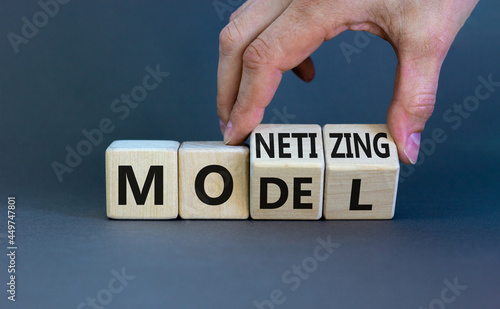 Monetizing model symbol. Businessman turns wooden cubes and changes the word 'Monetizing' to 'Model'. Beautiful grey table, grey background, copy space. Business and monetizing model concept.