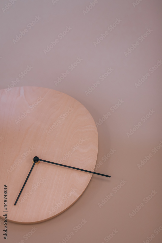 Minimalistic wooden wall clock on a neutral beige background. Modern style interior details. Vertical Minimalistic wooden wall clock on a neutral beige background. Modern style interior details. Vertical