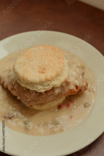 Fried chicken biscuit smothered in gravy on white plate