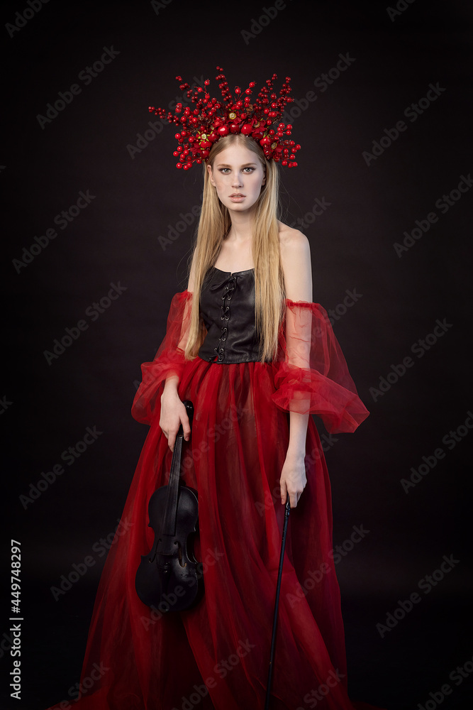 A beautiful girl in a stylized costume with a crown on her head and a violin in her hands. Fashion shooting. Fashionable image. Beauty photography for a book or magazine. A beautiful girl in a stylized costume with a crown on her head and a violin in her hands. Fashion shooting. Fashionable image. Beauty photography for a book or magazine.