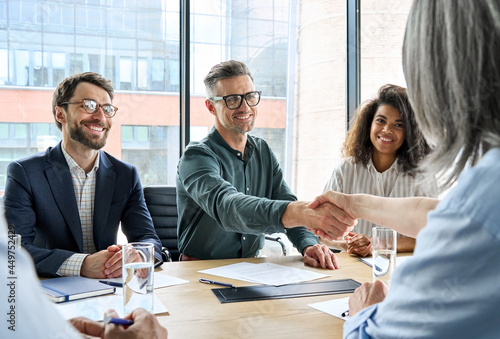 Happy businessman and businesswoman shaking hands at group board meeting. Professional business executive leaders making handshake agreement successful company trade partnership handshake concept. photo