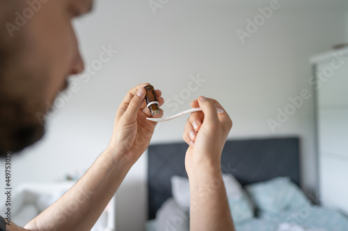 over the shoulder view on hands of unknown caucasian man preparing medicine drops in the plastic spoon vitamins and pro-biotic for newborn baby with copy space