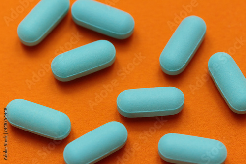 scattered blue pills on a contrasting bright orange background