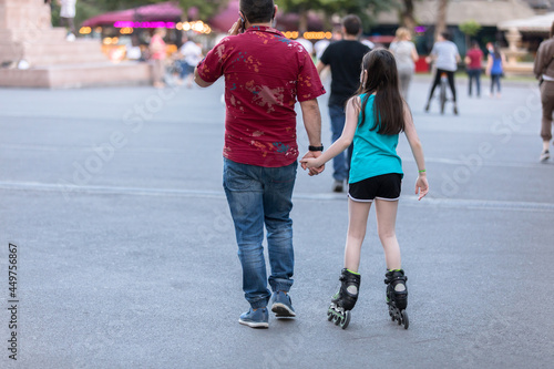 father teaches his daughter to ride roller skates