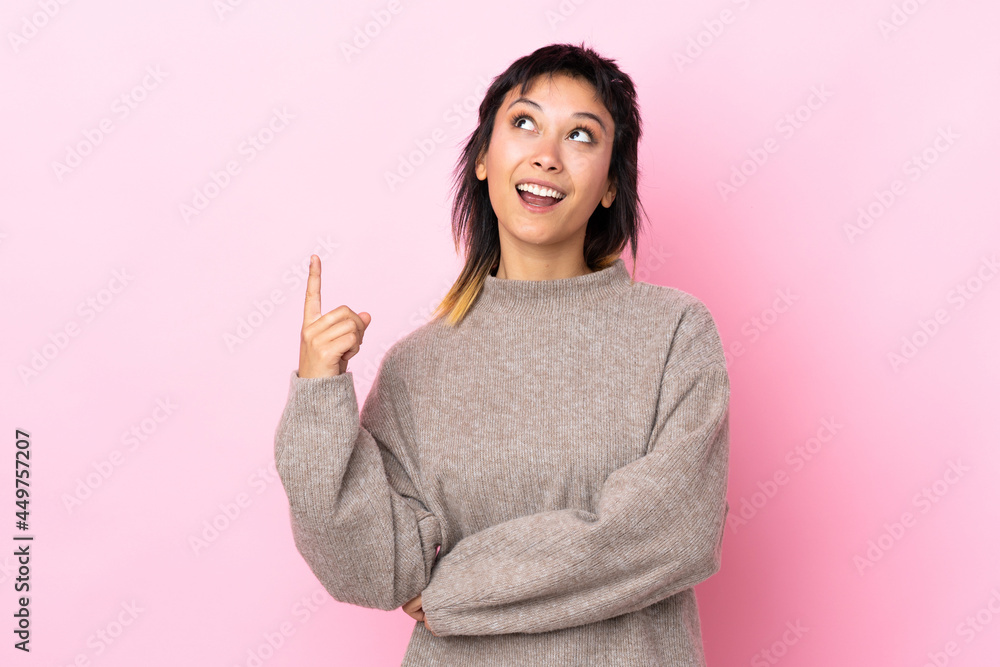 Young Uruguayan woman over isolated pink background pointing up and surprised Young Uruguayan woman over isolated pink background pointing up and surprised